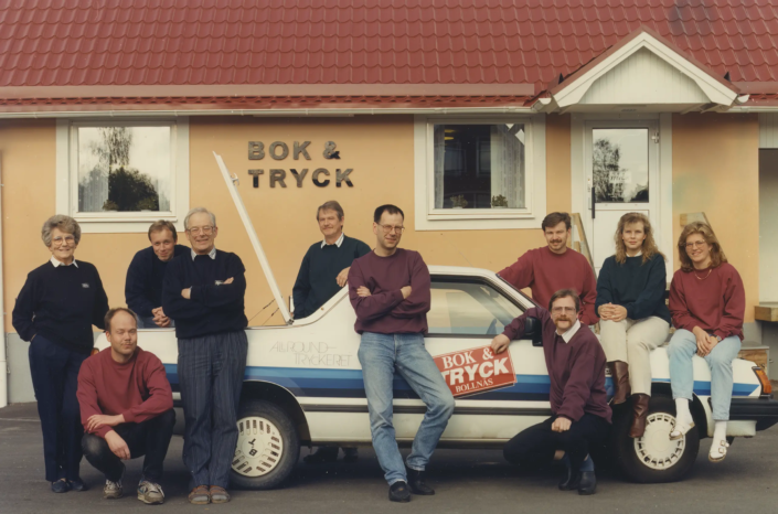 1990-tal. Dåtidens Bok & Tryck poserar på och omkring firmabilen.