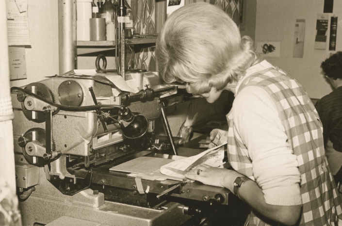1960-tal. Inga Mårtensson fäster guldfolie på en bokpärm vid förgyllpressen.
