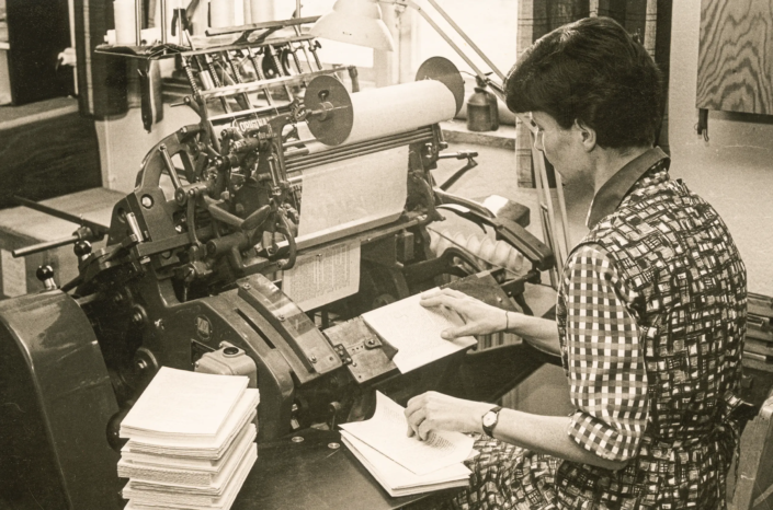 1960-tal. Siri Larsson trådhäftar ark till bokblock i en linnétrådshäftmaskin.