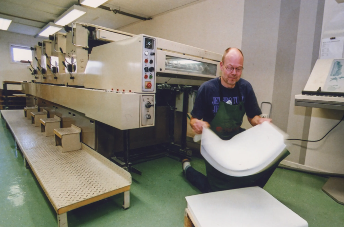 2000-tal. Tryckare Lars "Lasse" Forslin förbereder papper till tryck i fyrfärgstryckpressen.