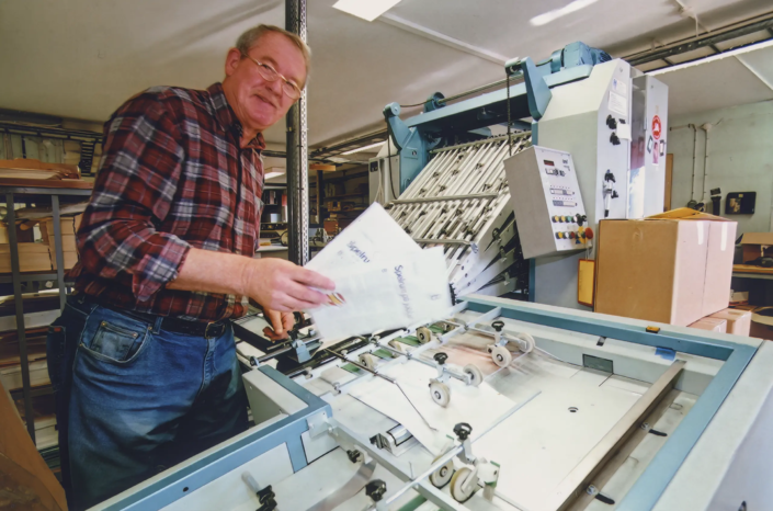 2000-tal. Arne Blom producerar broschyrer i plock- och broschyrhäftmaskinen.